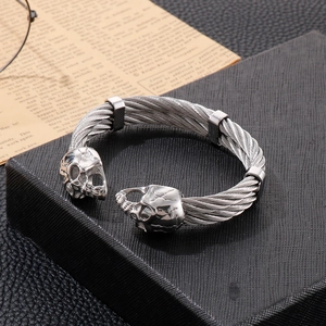 Detailed macro shot of a silver punk skull wire bangle on a black textured gift box