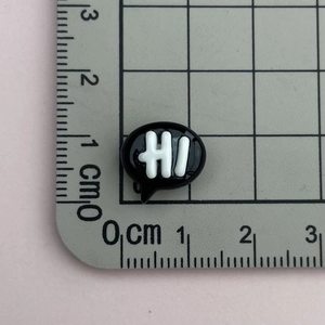 Makroaufnahme eines schwarzen Harz-Hi-Anhängers mit 1,1 cm Größe auf einem Lineal