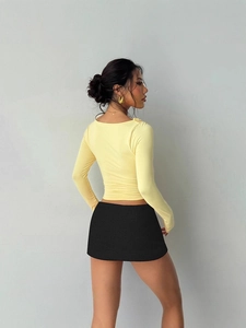 Slim fit light yellow long sleeve top with ruffle edges and black mini skirt