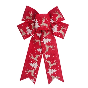 Detailed view of red burlap Christmas bow featuring golden reindeer and white tree patterns