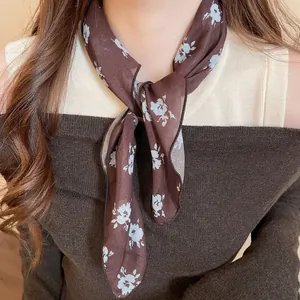 Brown silk scarf with light blue floral print worn by a woman with a knit sweater