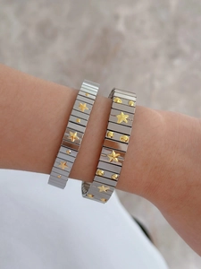 Detail of silver stainless steel stretch bracelets with gold star and dot relief accents