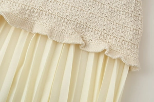 Detailopname van beige gebreide top en geplooide rokstof textuur met verfijnde stiksels