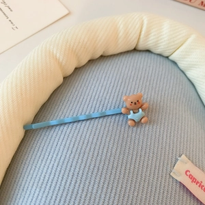 Gros plan d'une pince à cheveux ours bleu sur un fond de tissu texturé doux