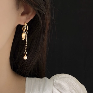 Gros plan de boucles d'oreilles poisson rouge doré avec perles pendantes sur modèle