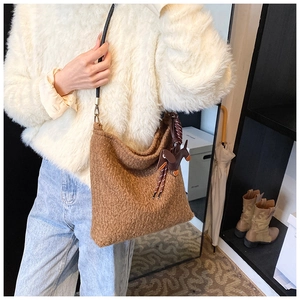 Close-up of brown wool shoulder bag with teddy texture and cute dog charm on female model