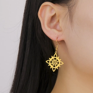 Close-up of a gold witch knot moon earring worn by a model with long dark hair