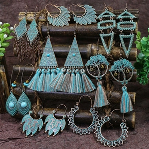 Detailed set of bohemian earrings with turquoise beads and tassels on a wooden stand