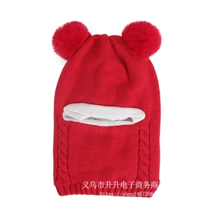 Detail of red cable-knit baby balaclava hat with double pompoms and white fleece lining
