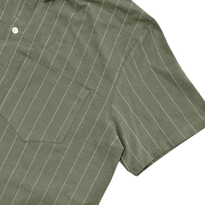 Close-up of military green striped shirt featuring chest pocket and buttons texture