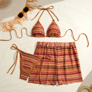 Three-piece striped crochet bikini set with halter top and shorts on beach background