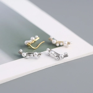 Macro shot of gold and silver branch ear cuffs with white pearls and sparkling crystals