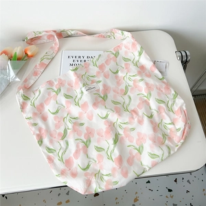 Detailed view of pink floral canvas tote bag featuring a brand label and wide shoulder strap