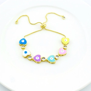 Detail of gold plated heart evil eye bracelet with colorful enamel and crystals on white dish