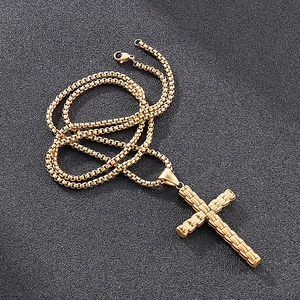 Vue détaillée du pendentif croix en acier doré poli avec chaîne maille vénitienne
