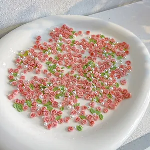 Macro view of pink resin roses with green leaves and white pearls for DIY nail art
