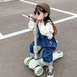 Primer plano de niña con gorro de punto marrón sentada en un patinete verde claro