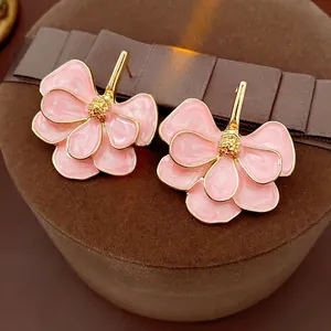 Vintage-style pink flower earrings with gold-plated edges on a brown velvet box