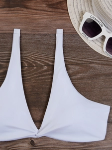 Dettaglio di un top bikini bianco a incrocio con cappello di paglia e occhiali retrò