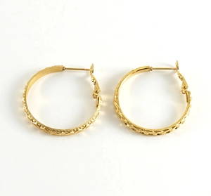Detail shot of golden hoop earrings featuring a hammered texture and hinge closure