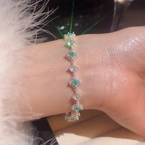 Detailed view of silver bracelet with green emerald-cut stones and white zircon crystals