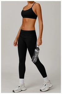 Detail of high-waisted black yoga set with crossover waistband and U-neck sports bra
