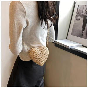 Golden heart-shaped cutout chain bag shown cross-body style against a minimalist wall
