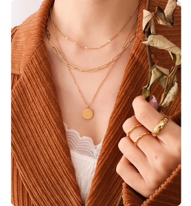 Macro detail of gold Carpe Diem coin pendant on layered paperclip and fine chain necklace