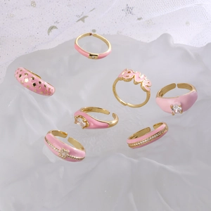 Pink enamel and gold rings set featuring heart, star, and love letter designs with cubic zirconia