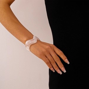 Close-up of wavy white acrylic bangle showing a fluid resin texture on model's wrist
