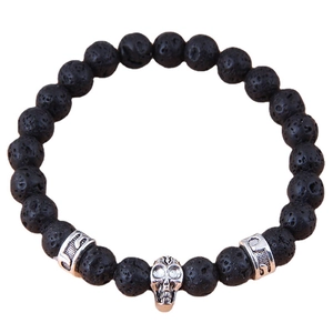 Black lava stone bracelet featuring silver skull charm and carved metal cylinder beads