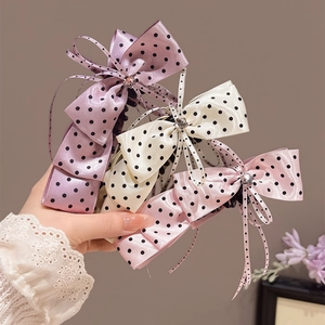 Vue détaillée de trois pinces à cheveux à nœud en satin à pois lilas, crème et rose