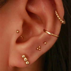 Close-up of minimalist gold plated S925 silver earrings set on a female model's ear