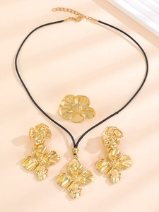 Detailed set of gold hollow flower jewelry with necklace, earrings, and ring in macro view