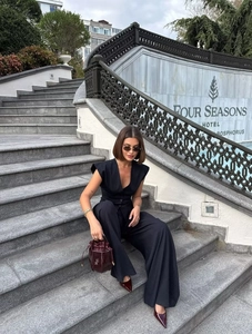 Street style shot of navy pinstripe vest and wide-leg trousers set with a red handbag