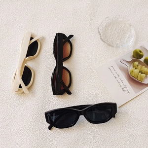 Detailed flat lay of vintage wide-frame cat-eye sunglasses in cream and black shades