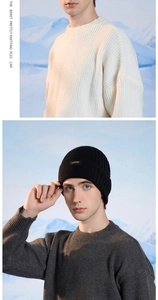 Detail of black ribbed knit beanie with brand patch shown in outdoor winter scenery