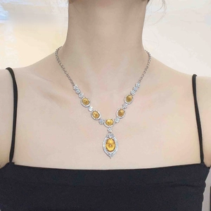 Detail of silver necklace featuring yellow oval stones and a teardrop pendant on a model