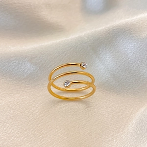 Details des goldenen dreifachen Spiralrings mit funkelnden Zirkoniasteinen auf Seide
