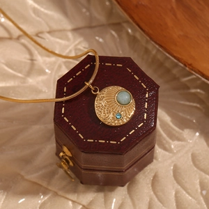 Close-up of 18K gold-plated compass pendant with sun moon stars and blue gemstones