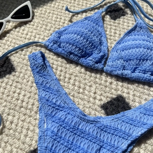 Close-up of blue smocked fabric texture on a two-piece bikini set with retro sunglasses