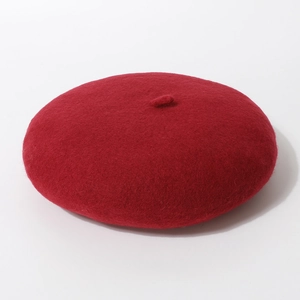 Detail van de dieprode wollen baret met zachte textuur en klein steeltje bovenop