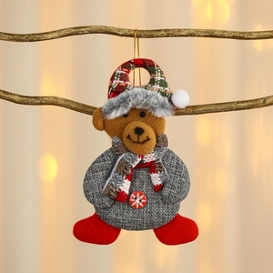 Detail of Christmas bear ornament with plaid hat and scarf hanging on a branch