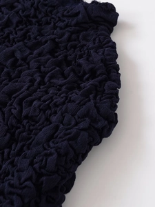Detailed macro view of dark blue popcorn fabric with 3D texture on a knit top