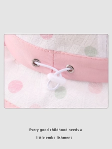 Dettaglio del cappello da sole a pois rosa con cordino regolabile e maglia traspirante