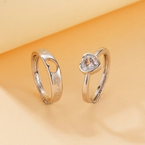 Macro shot of silver couple rings with heart zircon and love endless engraving detail