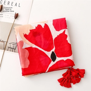 Detailed view of red floral print scarf with elegant fringe tassels and linen texture