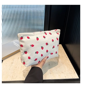 Detail of white corduroy pouch with red strawberry print and zipper closure