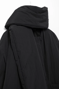 Detail einer glänzenden schwarzen Pufferjacke mit Schalkragen und Knopfverschluss