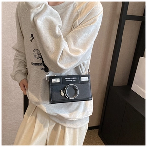 Macro detail of a vintage camera-shaped crossbody bag with lens and dial decorative features